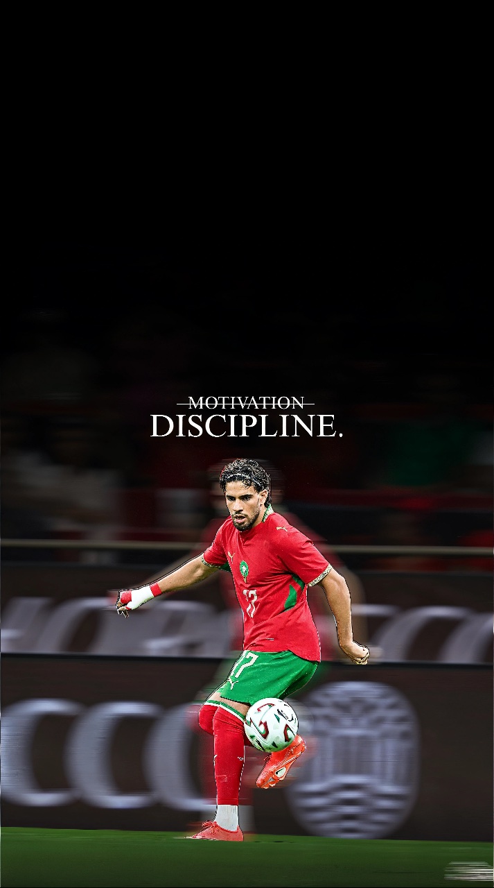 Moroccan footballer Ez Abde in a red and green kit controls the ball on a pitch beneath the words “MOTIVATION DISCIPLINE.”