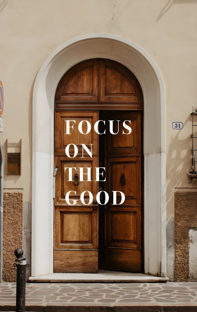 A warm wooden arched doorway with the white message “FOCUS ON THE GOOD” centered across the door.