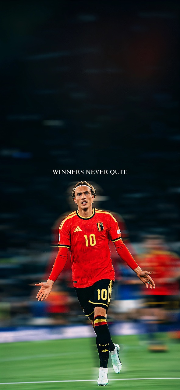 Mika Godts wearing Belgium’s red football kit on the pitch beneath the quote “Winners Never Quit.”