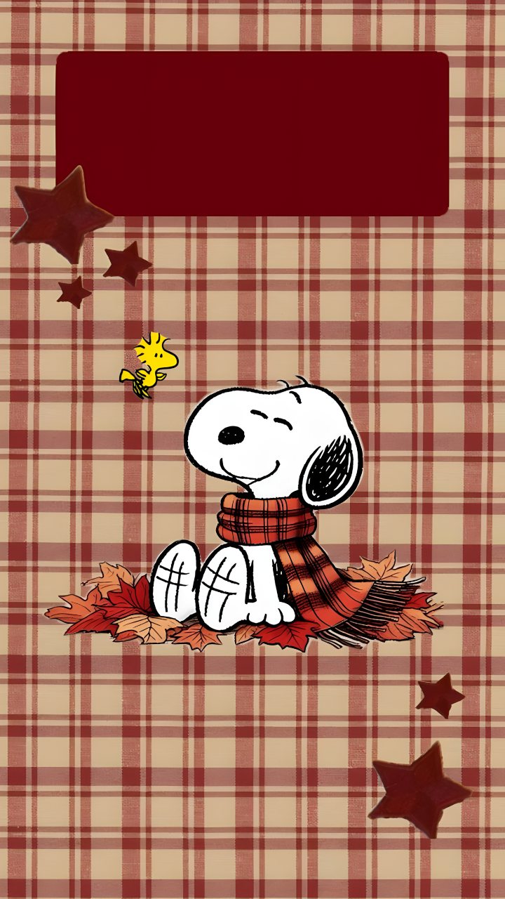 Snoopy wearing a red scarf sits on autumn leaves against a red and beige plaid background with stars and a blank burgundy panel.
